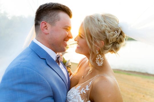Couple smiling face to face at sunset beside a lake