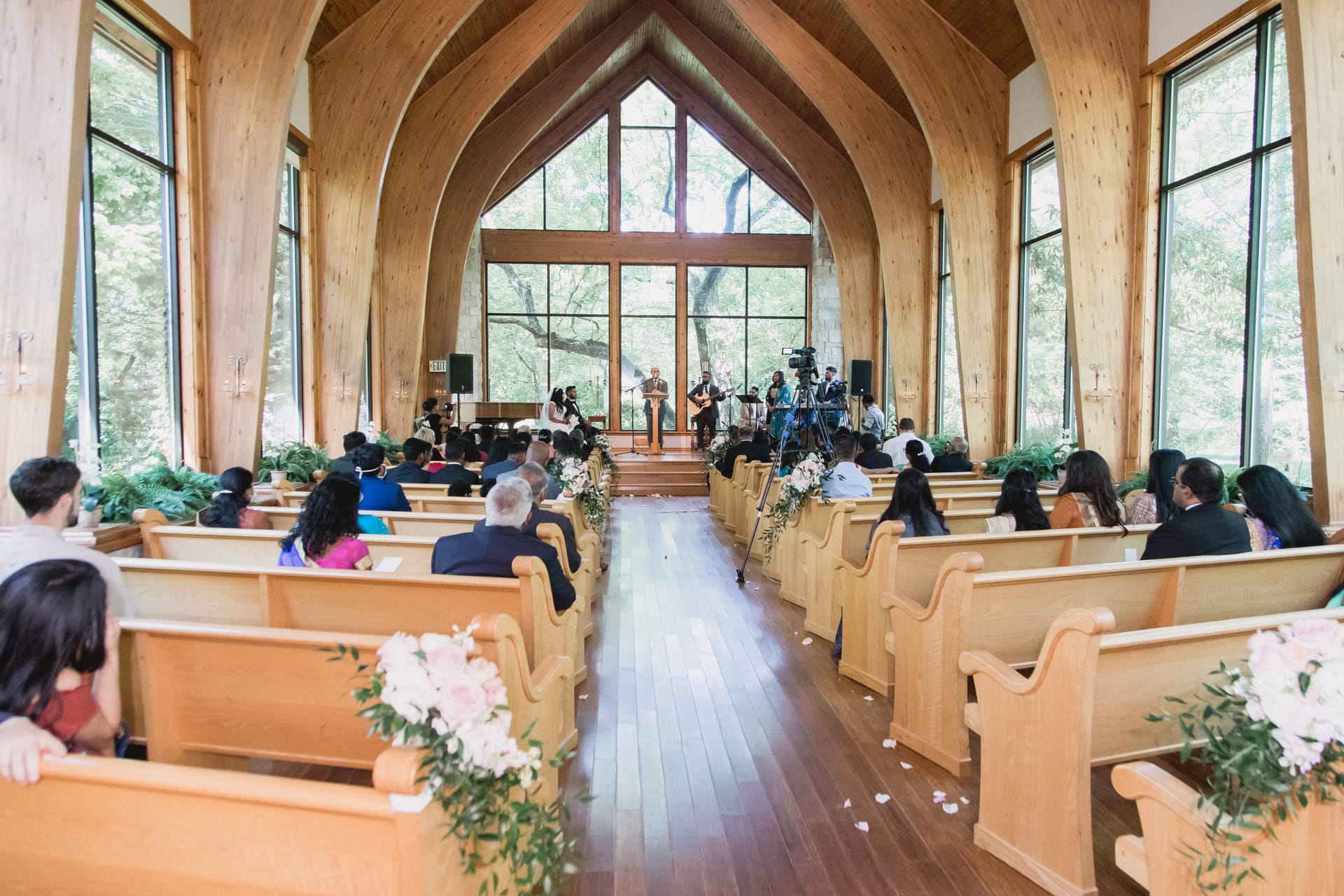 Guests seated in wooden pews inside a glass-walled chapel