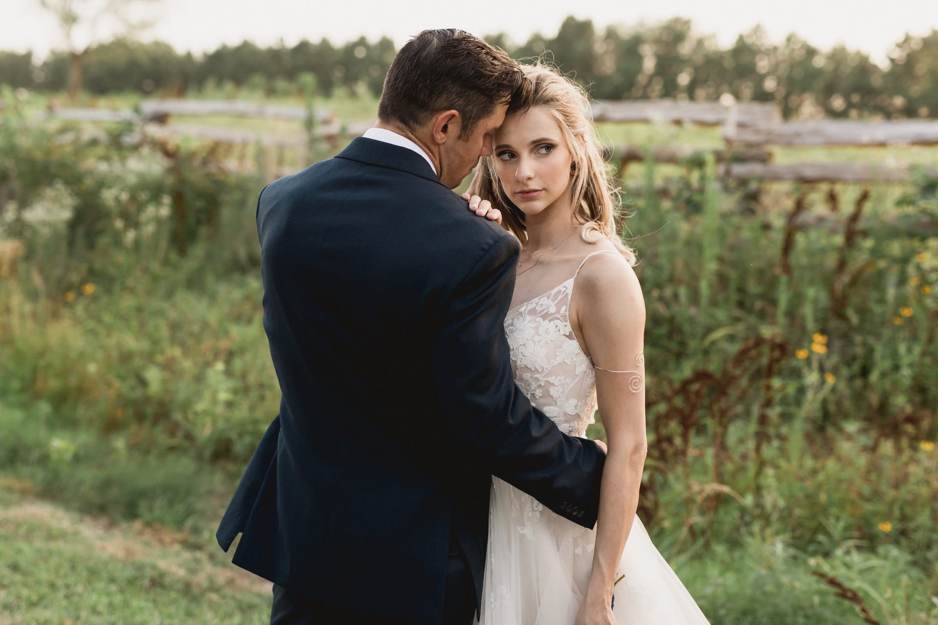 Groom holding the bride close in a field of tall grass